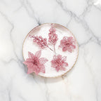 Blush pink glitter poinsettia and berry decorations arranged on marble plate - elegant festive florals for Christmas styling