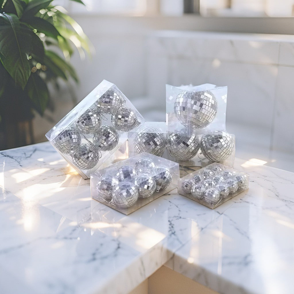 Set of silver mirrored disco ball ornaments in assorted sizes arranged on a marble surface - modern festive décor styling