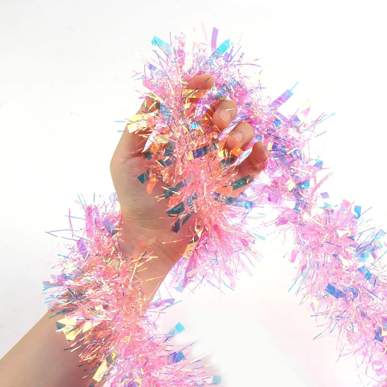 Hand holding pink iridescent Christmas tinsel – soft metallic finish
