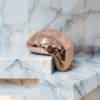 Bronze melting disco ball reflecting warm light on a marble surface, modern festive décor accent
