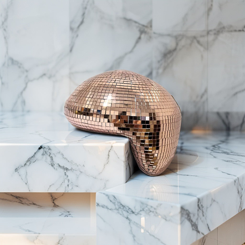 Bronze melting disco ball reflecting warm light on a marble surface, modern festive décor accent
