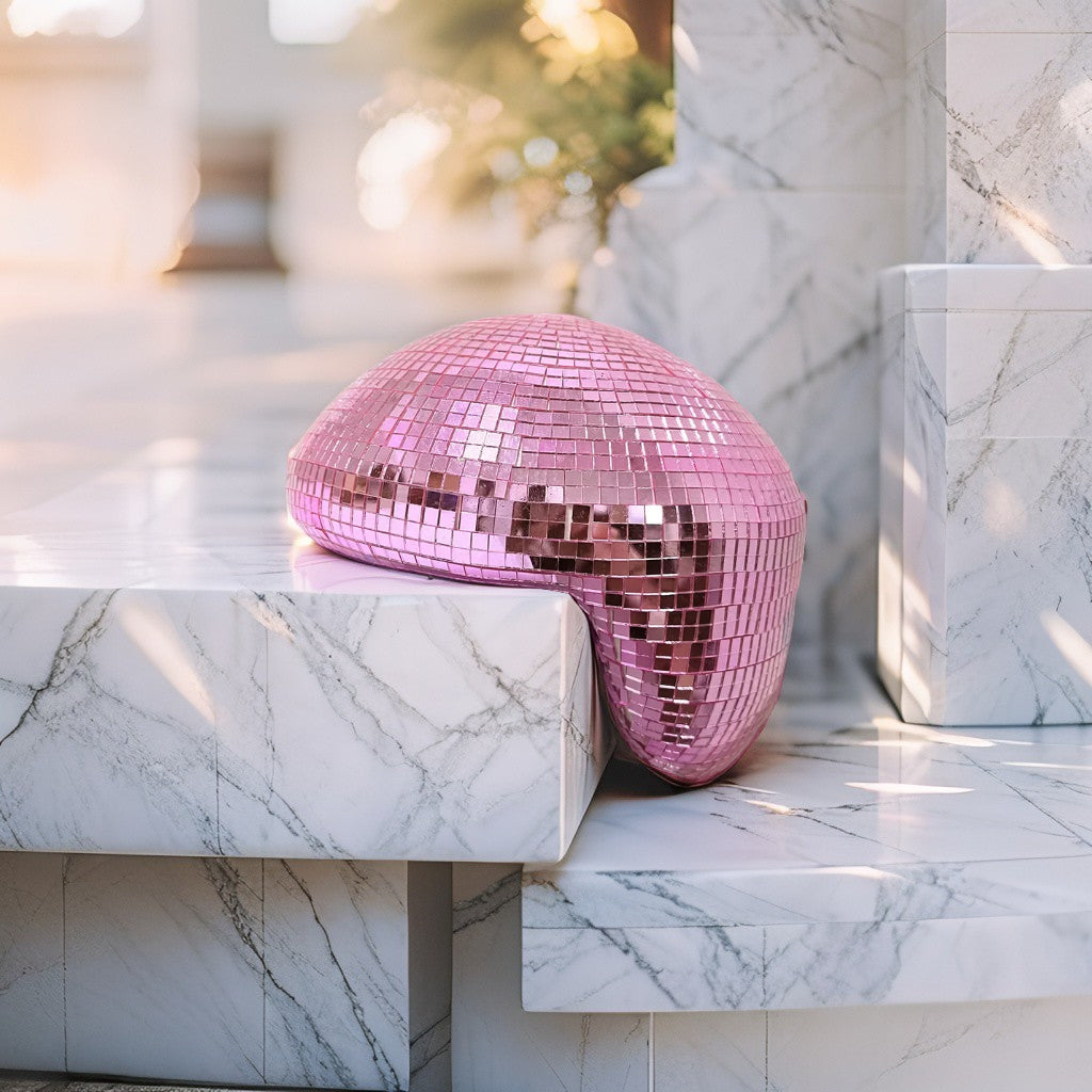 Pink melting disco ball reflecting soft light on a marble backdrop, modern Christmas décor accent