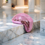 Pink melting disco ball reflecting soft light on a marble backdrop, modern Christmas décor accent