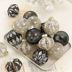 Nordic Noel Christmas baubles in black, silver, and champagne gold finishes arranged on a neutral tray - elegant mixed-texture ornaments for refined festive décor