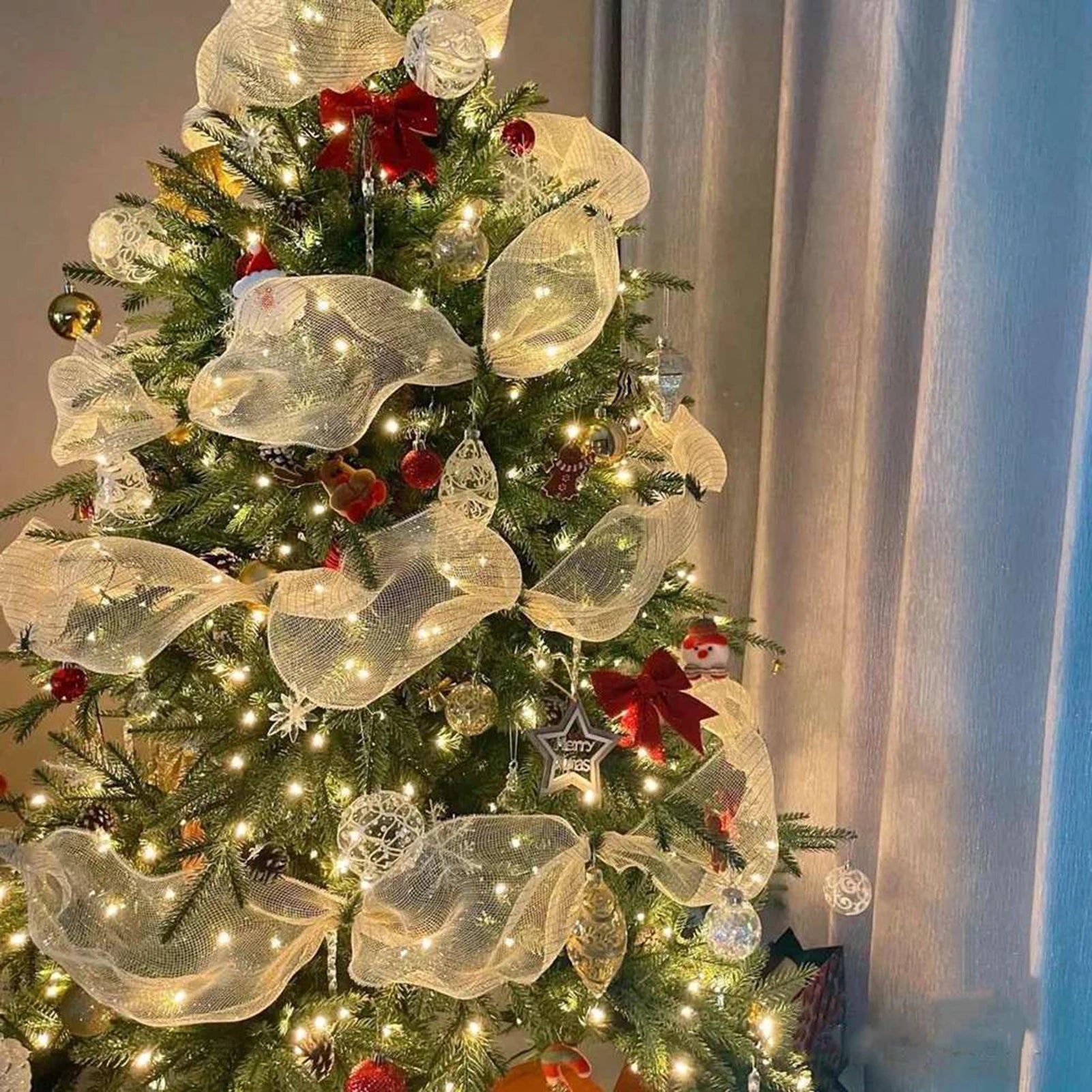 White tinsel glitter ribbon woven through a decorated Christmas tree with warm lights and ornaments, elegant festive décor accent