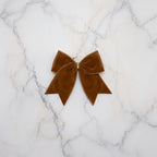 Chocolate brown velvet bows styled on marble with ornaments - warm, sophisticated festive decoration