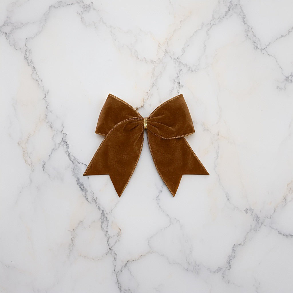 Chocolate brown velvet bows styled on marble with ornaments - warm, sophisticated festive decoration