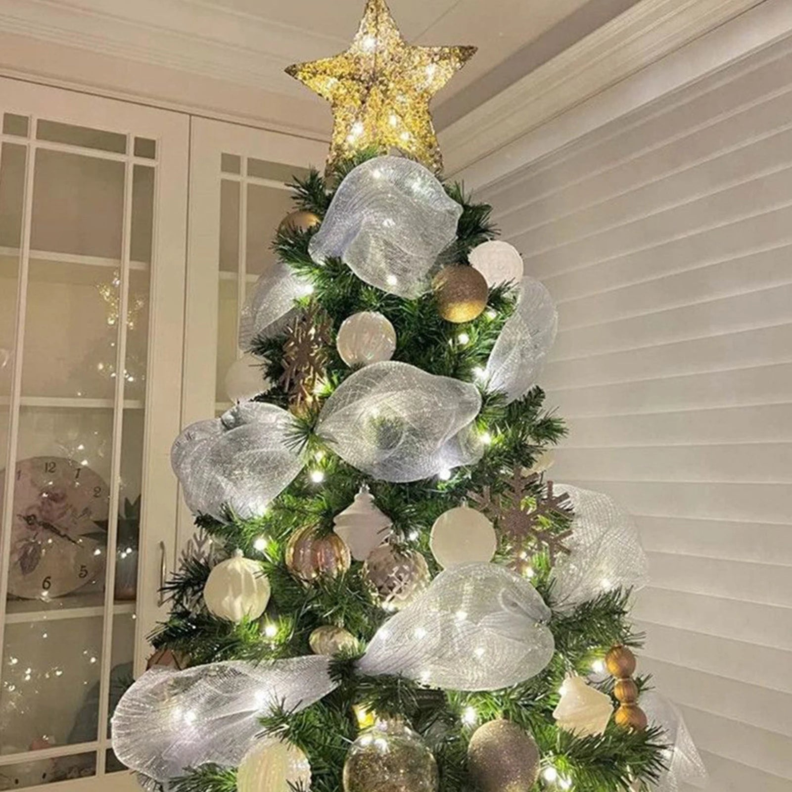 White tinsel glitter ribbon woven through a decorated Christmas tree with warm lights and ornaments, elegant festive décor accent